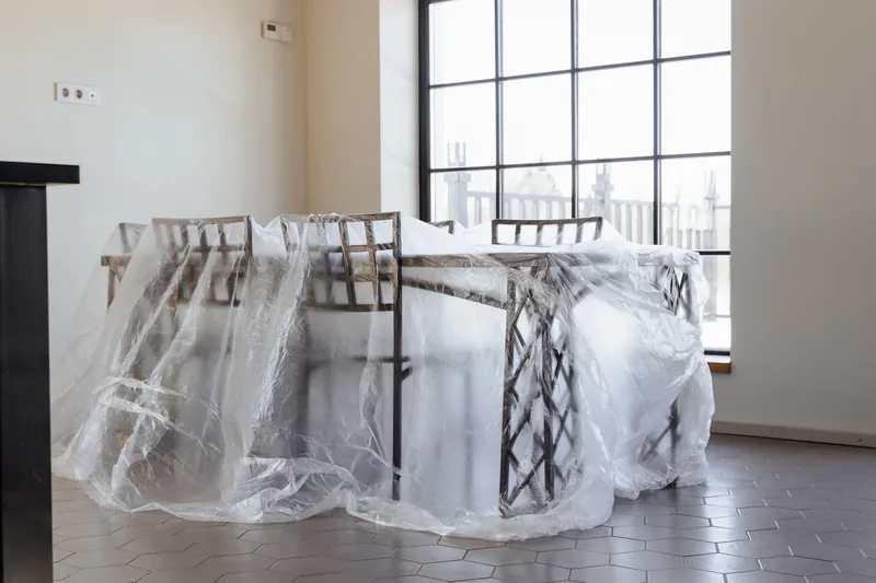 Dining chairs and table covered in plastic, a new home interior ready for moving in.