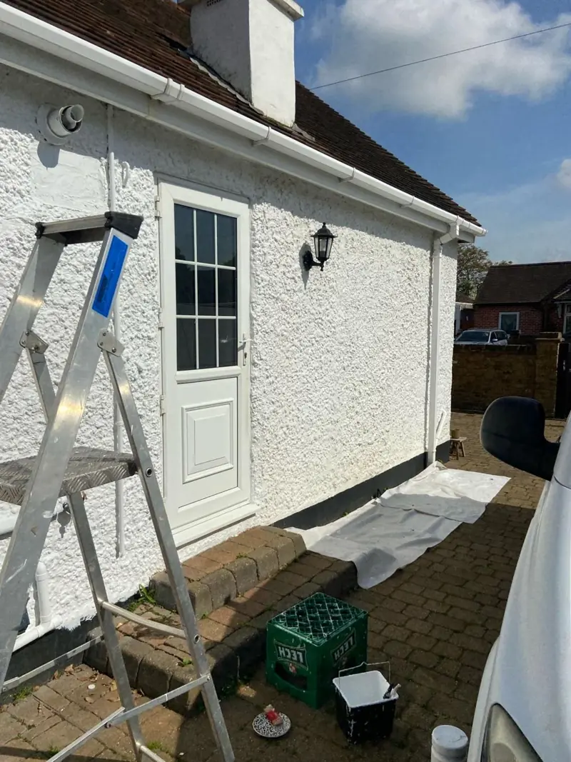 White rendered bungalow being repainted, ladders in place