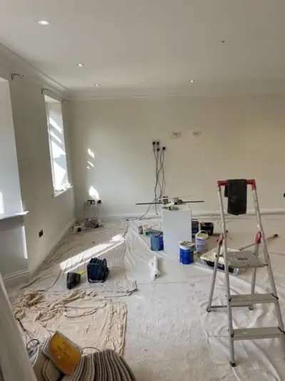 Bay-window living room being decorated, floor protected with dust sheets