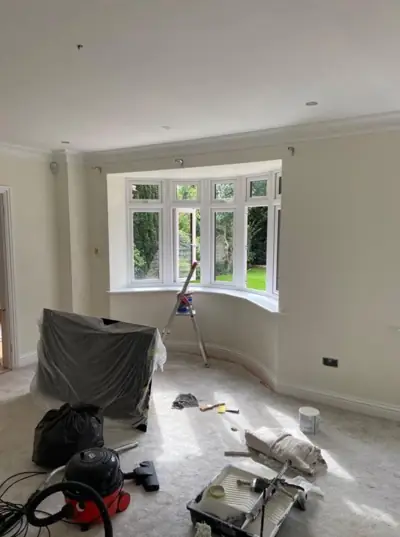 Bay-window living room being decorated, floor protected with dust sheets