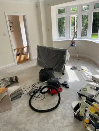Bay-window living room being decorated, floor protected with dust sheets
