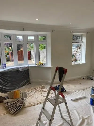 Bay-window living room being decorated, floor protected with dust sheets