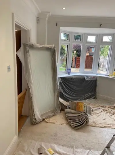 Bay-window living room being decorated, floor protected with dust sheets