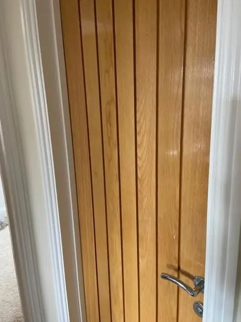 Close-up of an oak door with a lacquered finish beside white gloss architrave